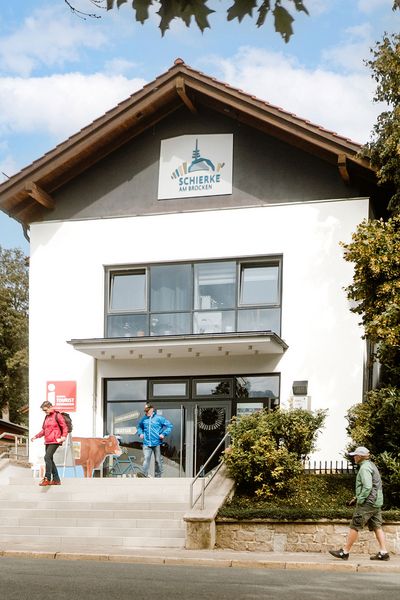 Vor dem Gebäude der Tourist-Information in Schierke gehen Besucher auf der Straße entlang. 