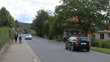 Die Brockenstraße in Schierke mit zwei Autos und Fußgängern